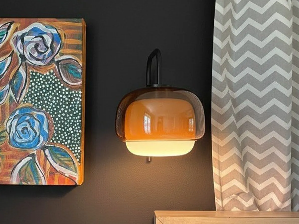 Lit orange Clinco lamp fully visible beside a painting, photographed by Jeff Sheehan