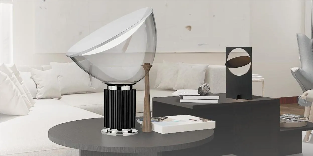 Lámpara de mesa en cromo y negro sobre una mesa de centro.