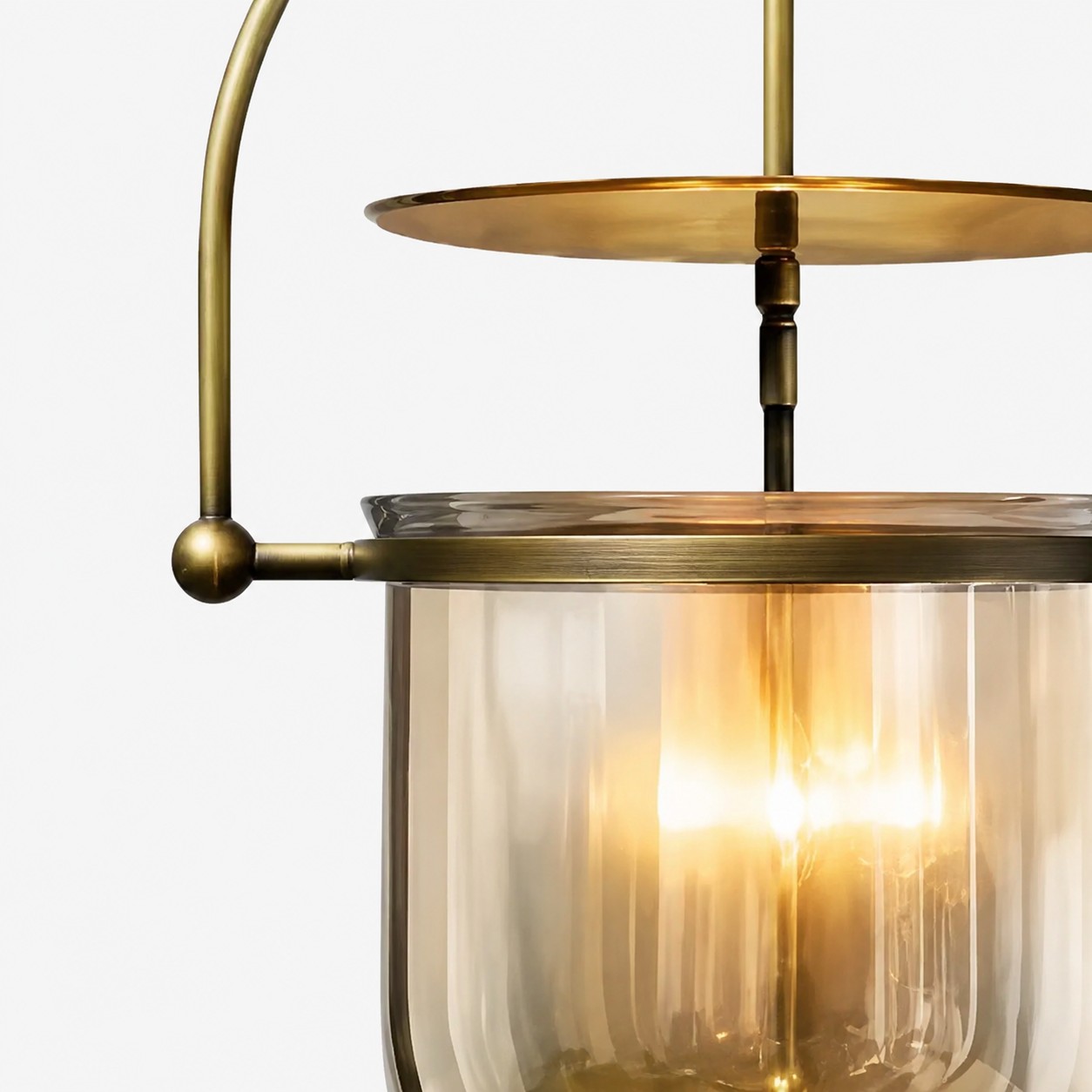 Gros plan sur l'abat-jour en verre côtelé et la structure métallique ajourée couleur laiton.
