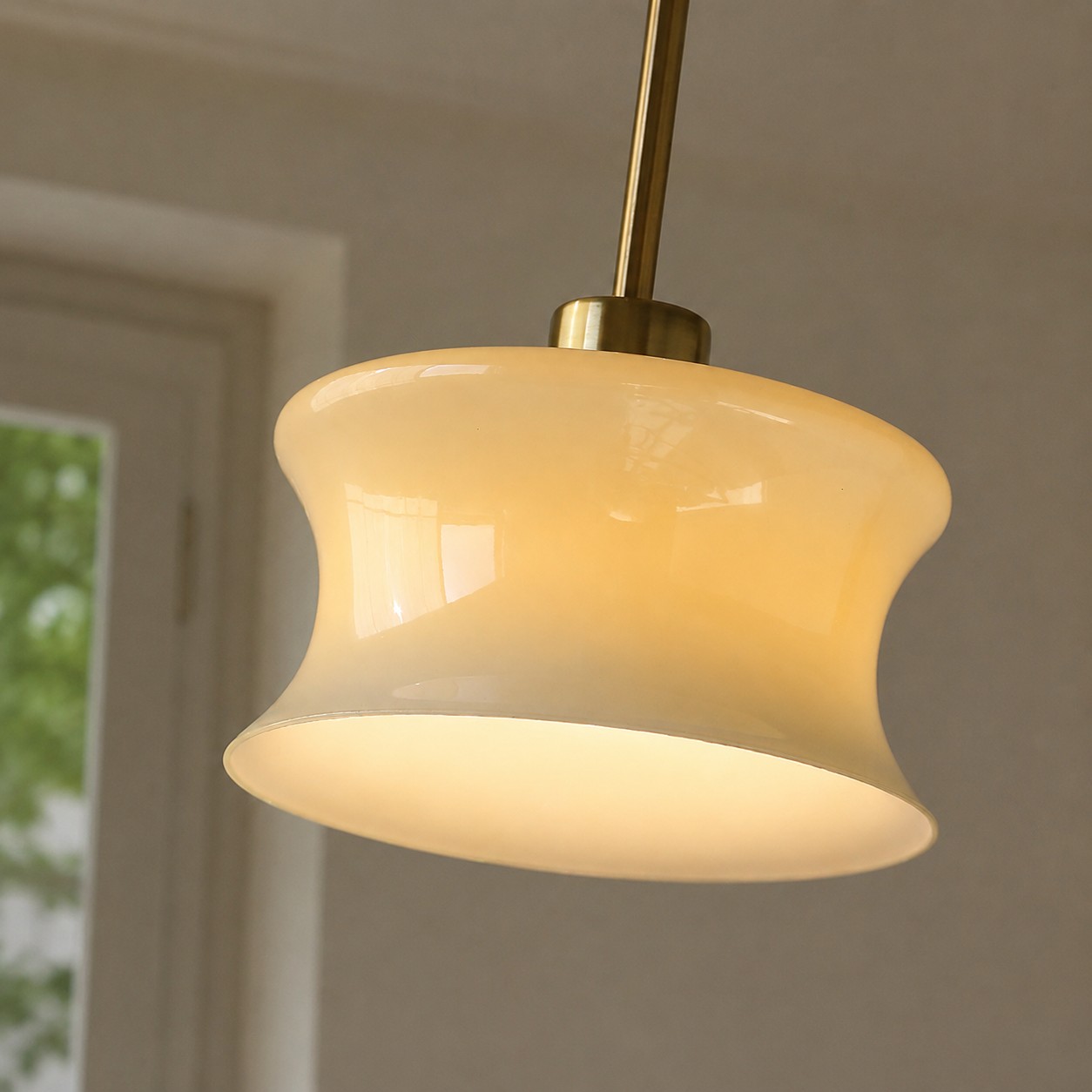 Nahaufnahme des gebogenen Glaspendelschirms, der warm leuchtet
