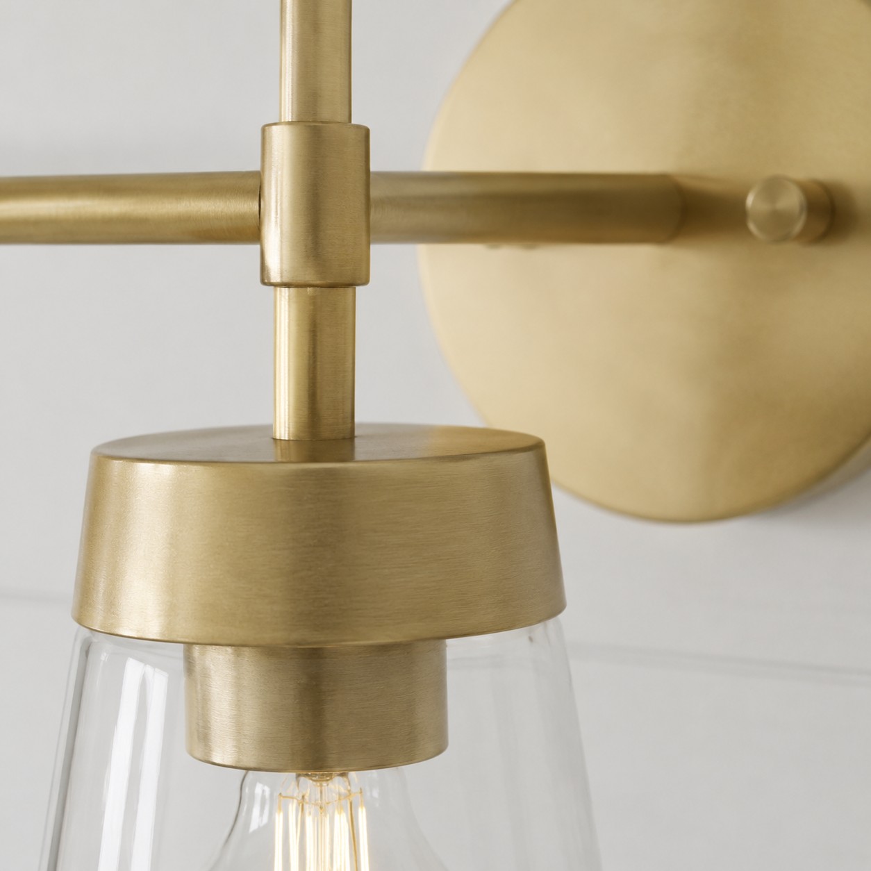 Close view of brushed brass joint and clear tapered glass shade