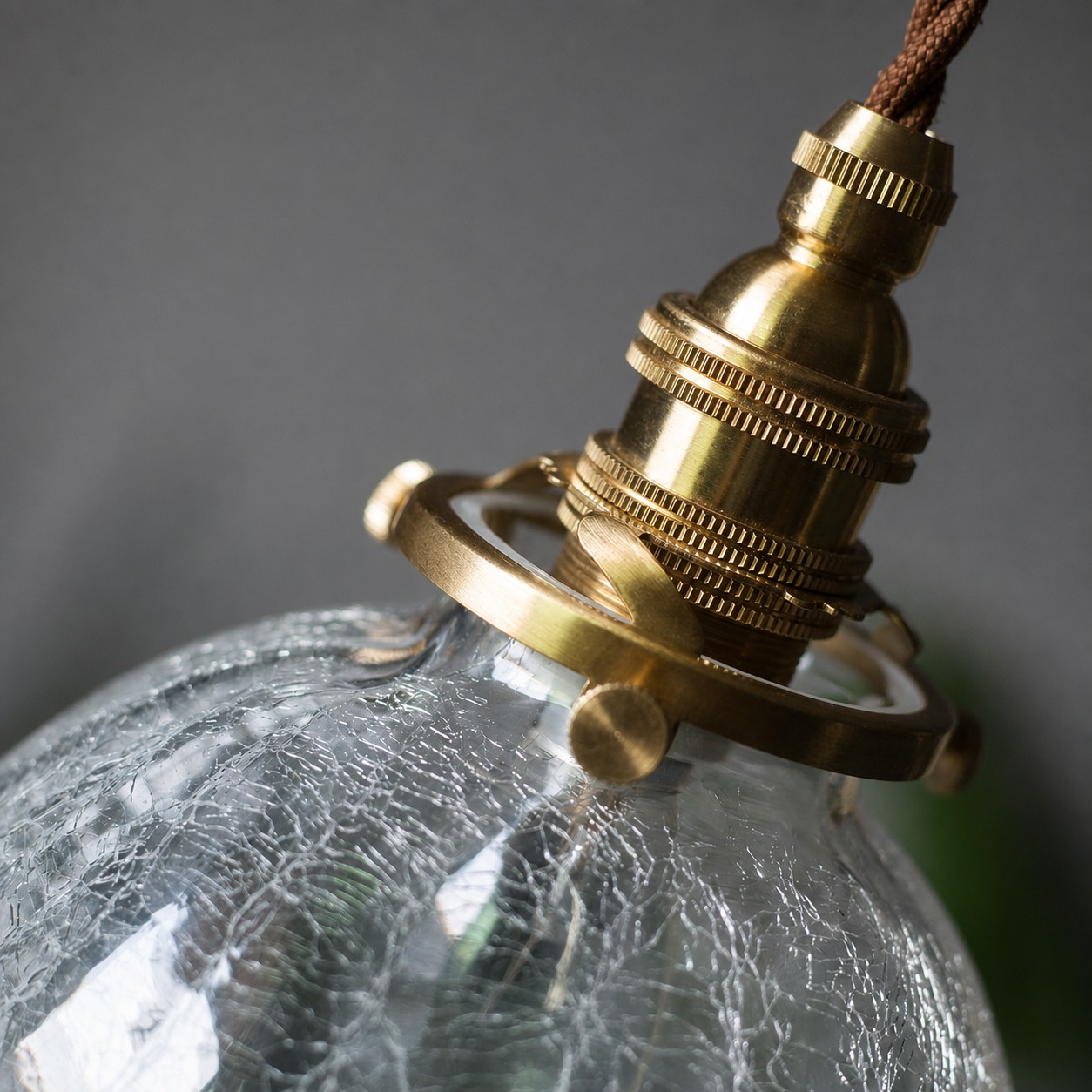 Brass-tone socket, ring, and side screws on the crackled glass globe pendant