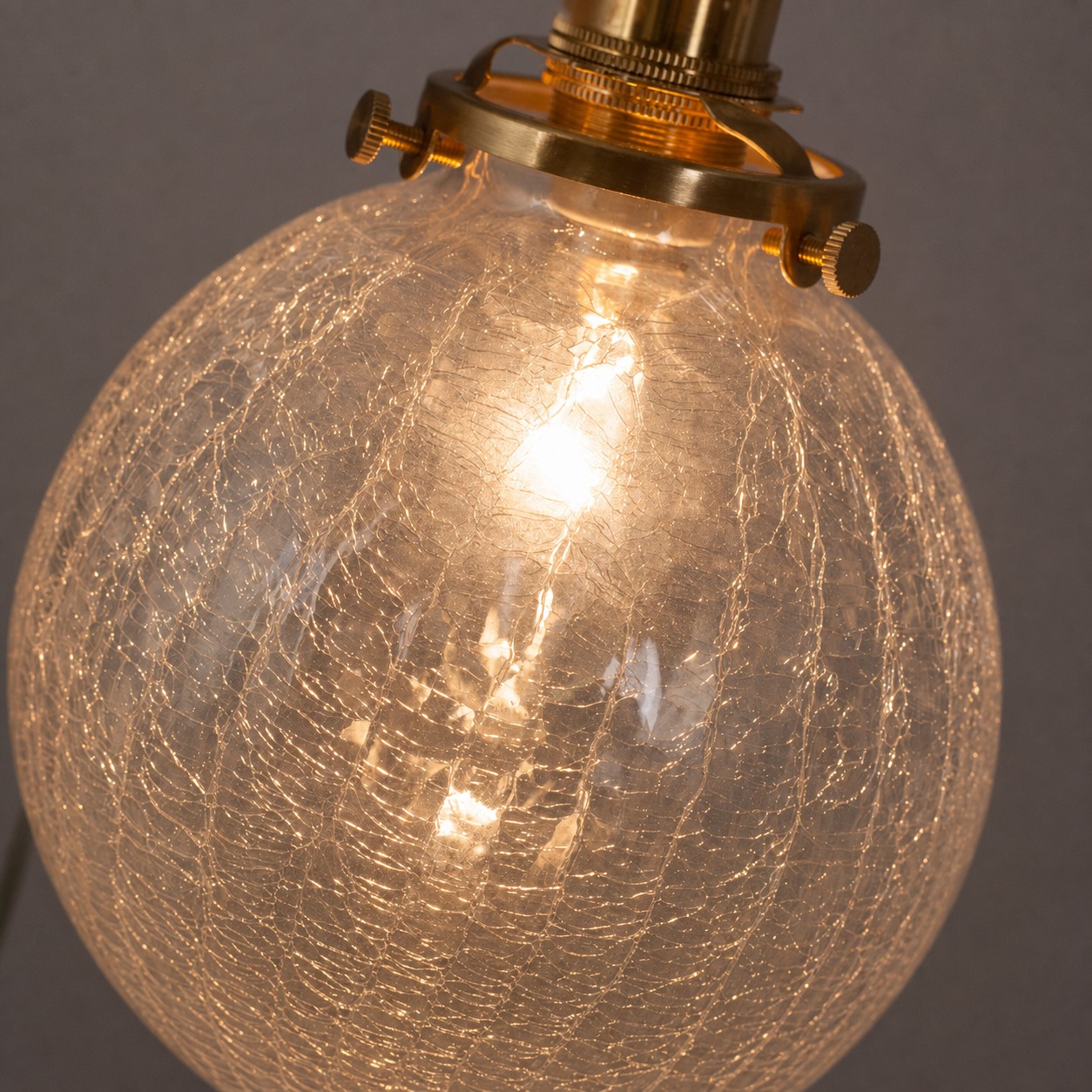 Lit crackled glass globe pendant showing layered glow through the shade