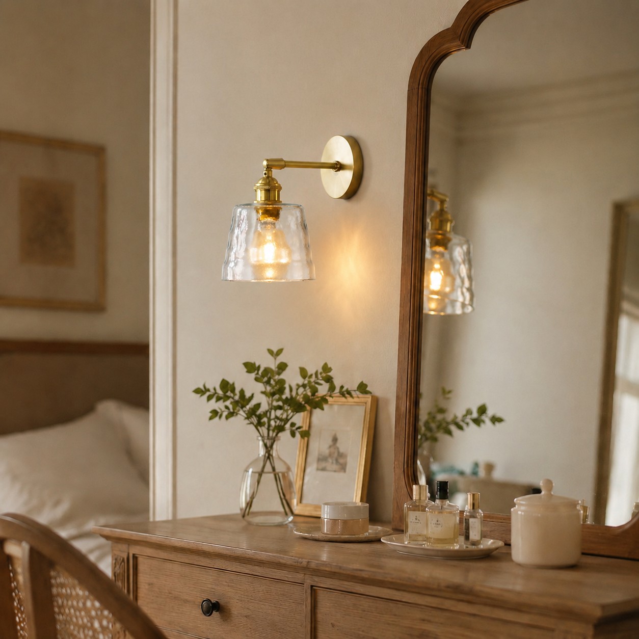 Brass wall sconce beside a bedroom dressing mirror