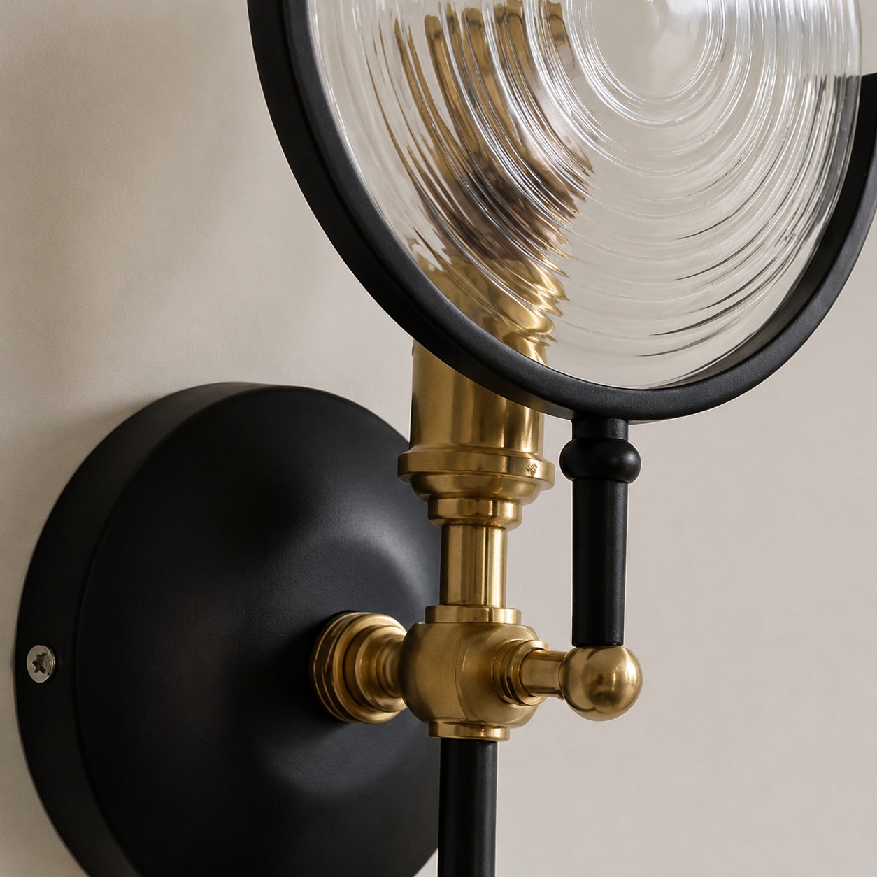 Low-angle detail of black backplate, aged-brass joint, and concentric glass ridges