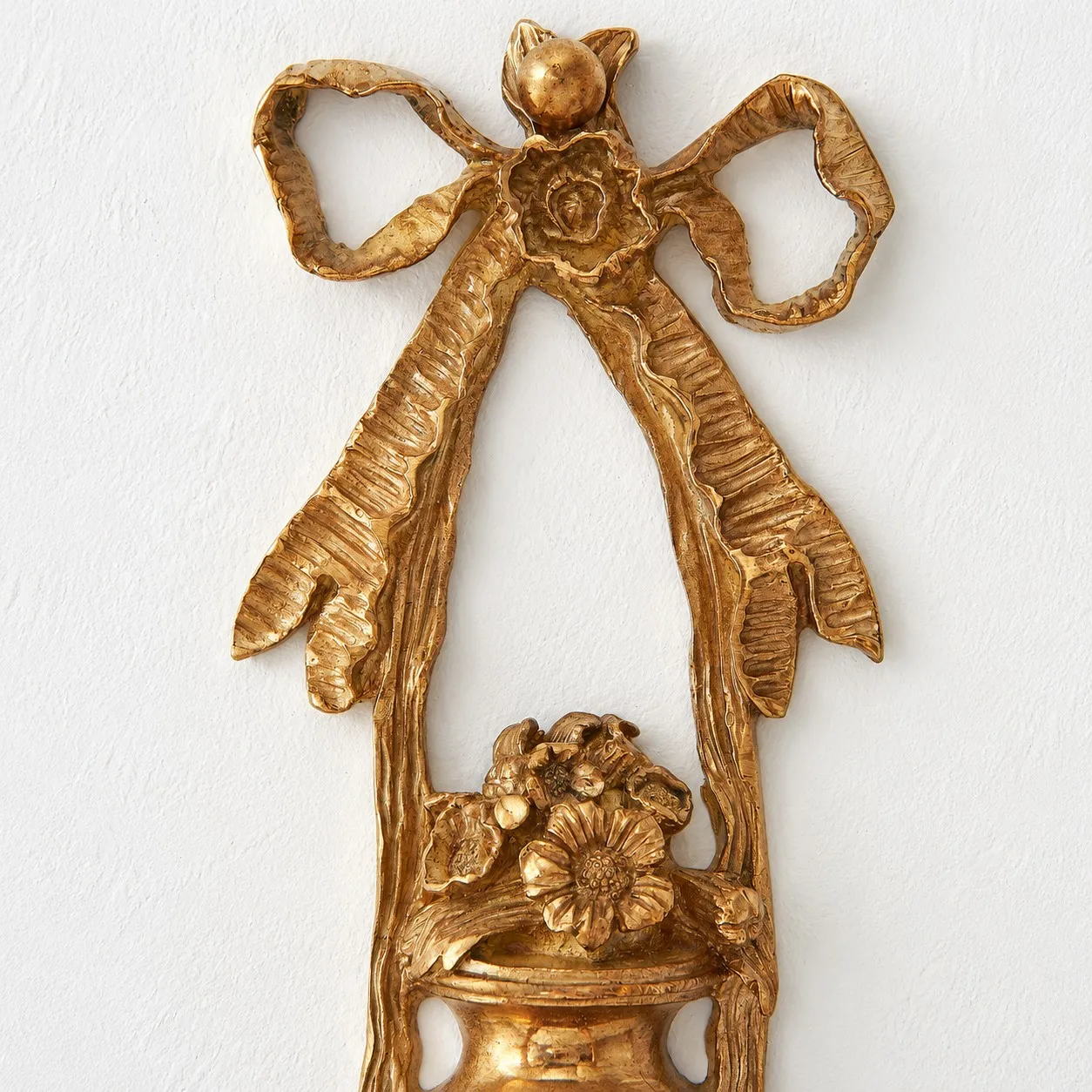 Close view of the ornate brass bow and floral wall plate