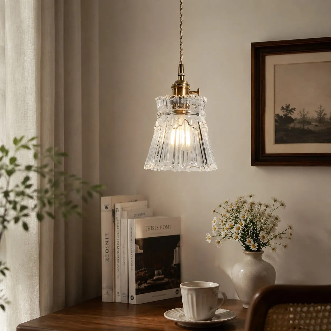 Style M ornate clear glass pendant beside books and tableware