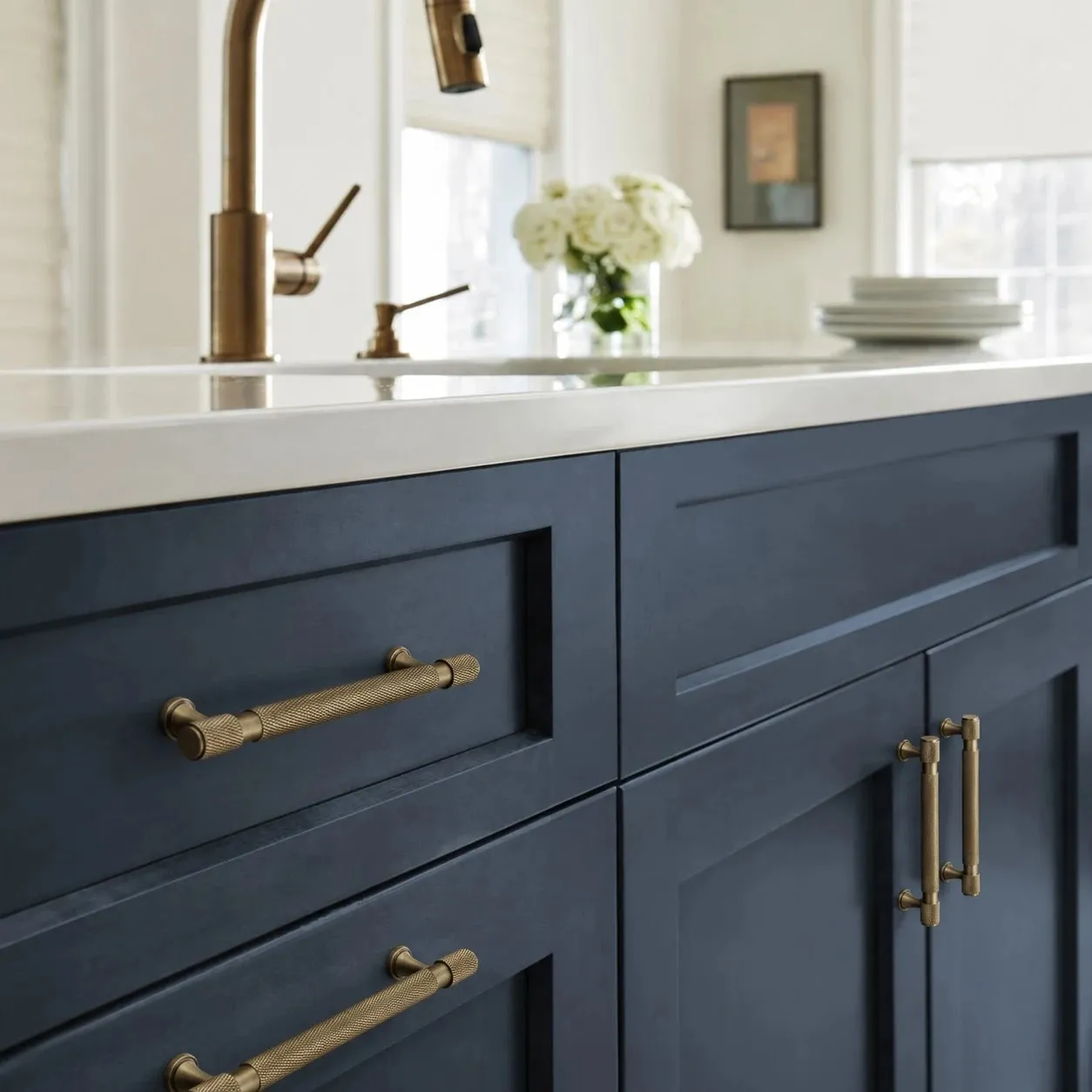 Antique brass pulls installed on blue kitchen cabinetry