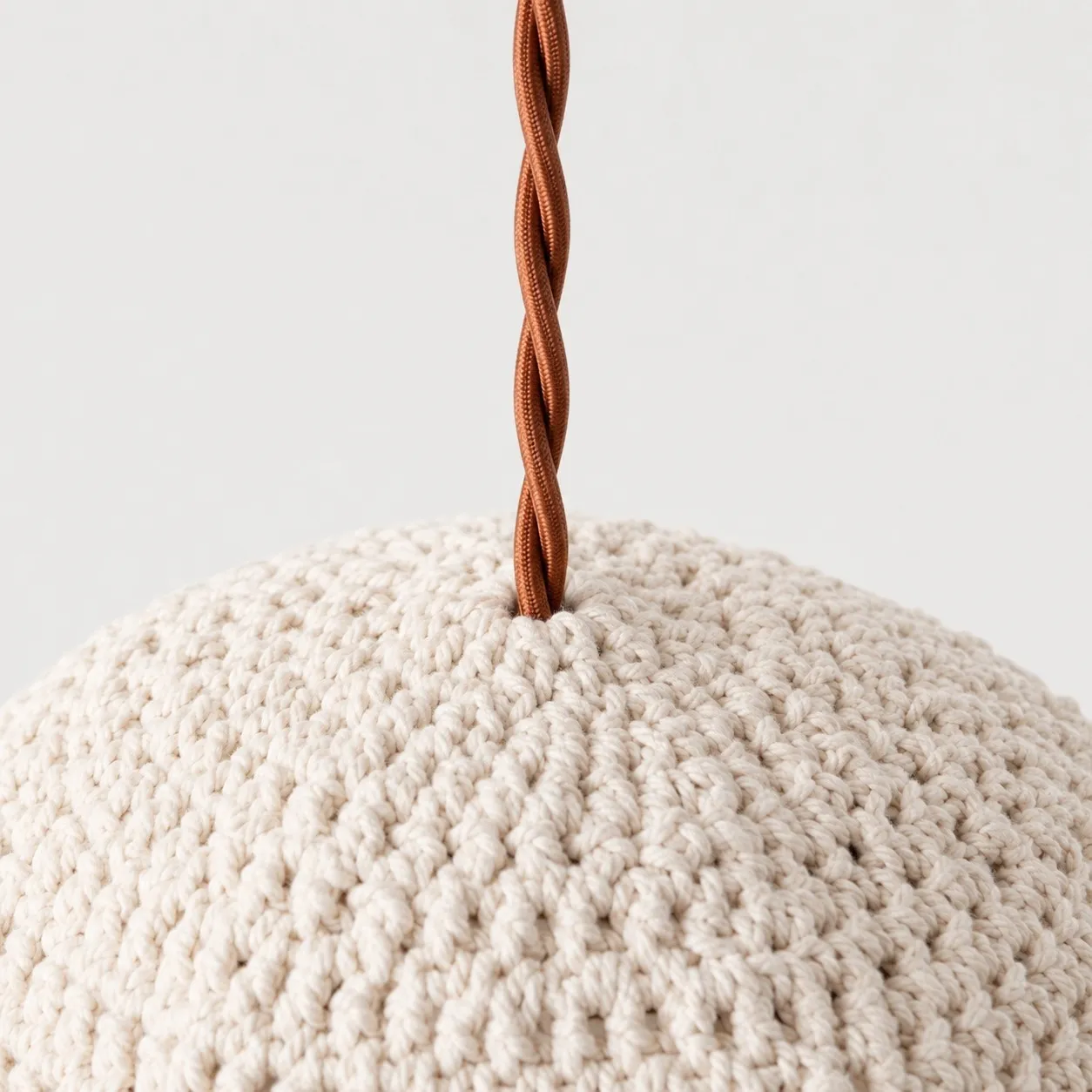 Close-up of twisted brown pendant cord entering the ivory handwoven shade