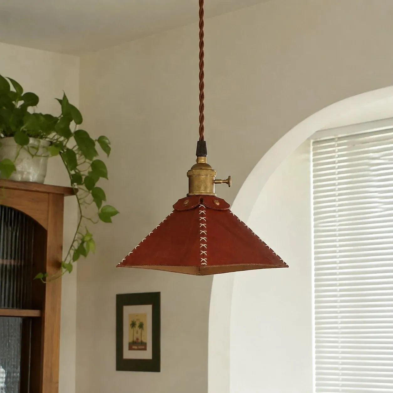 Leather pyramid pendant lamp near a bright window and plants