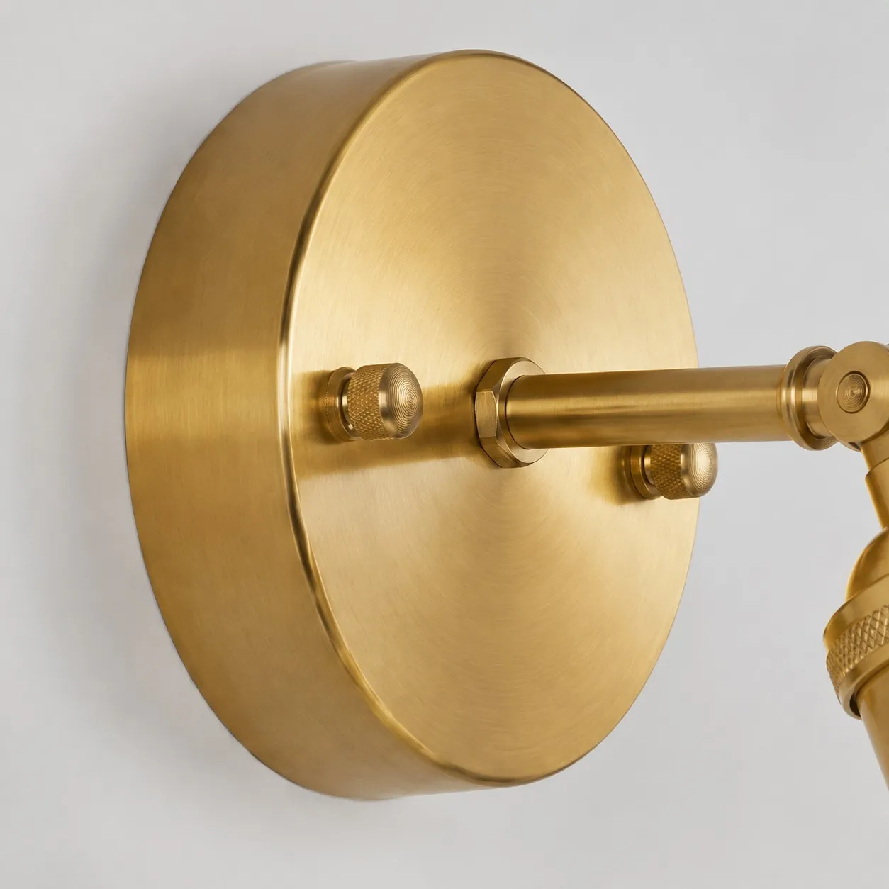 Close view of brushed brass round wall backplate and mounting screws