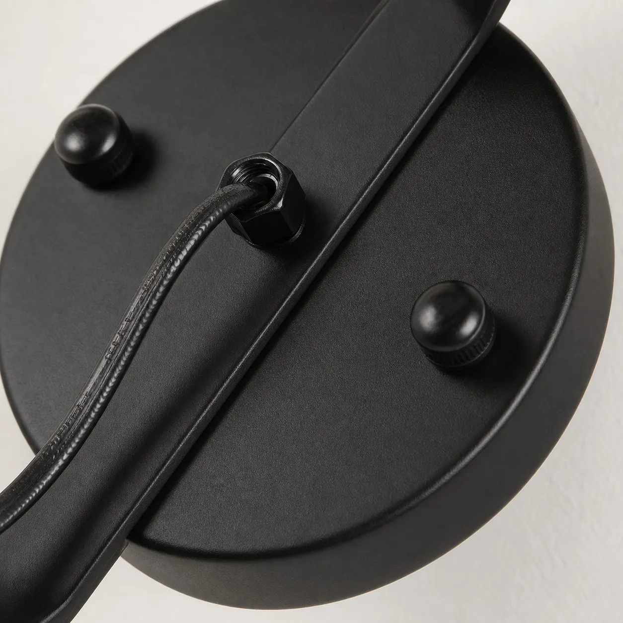 Close view of matte black round wall plate and cord detail