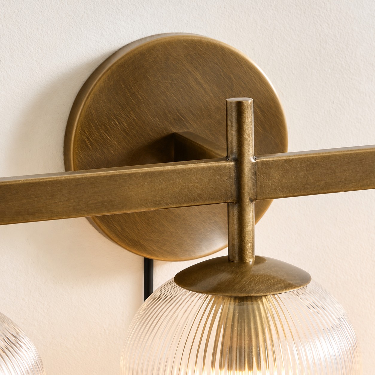 Close view of the tumbled-brass wall plate, bar joint and ribbed shade