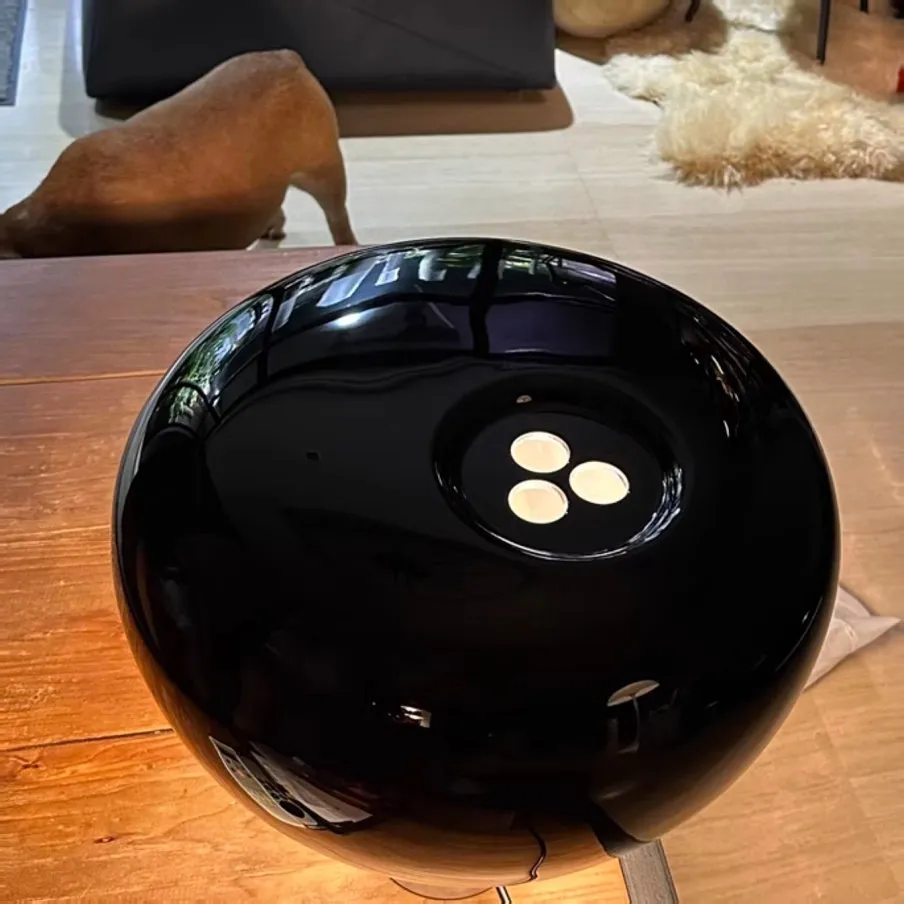 Candeeiro preto numa superfície branca ao lado de um livro
