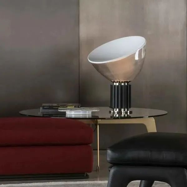 Lampe en bol noir allumée sur une table près d’un canapé rouge