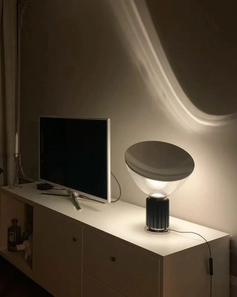 Lampe en bol noir allumée sur un meuble TV près d’un téléviseur