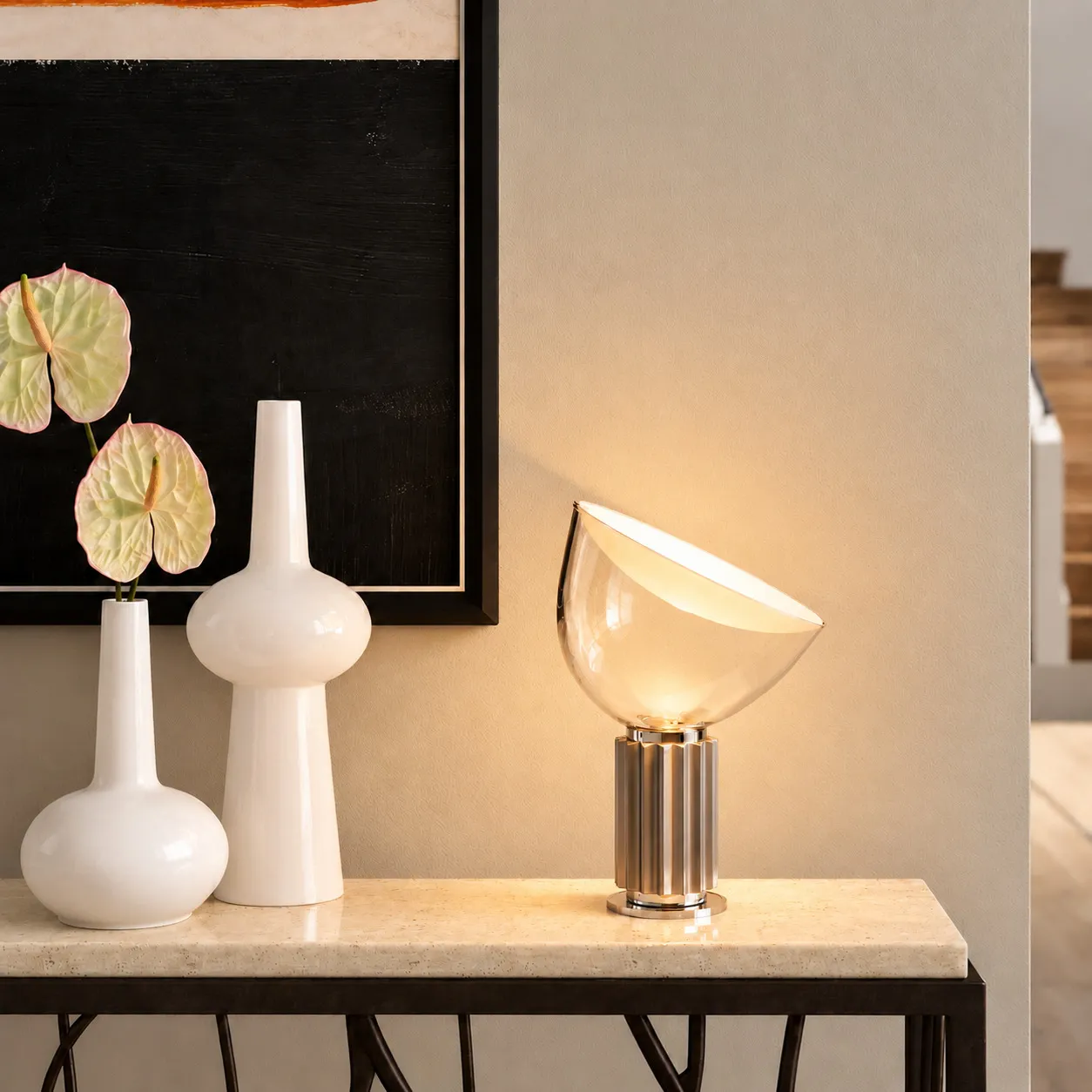Lampe en bol argenté allumée sur une console, près de vases blancs